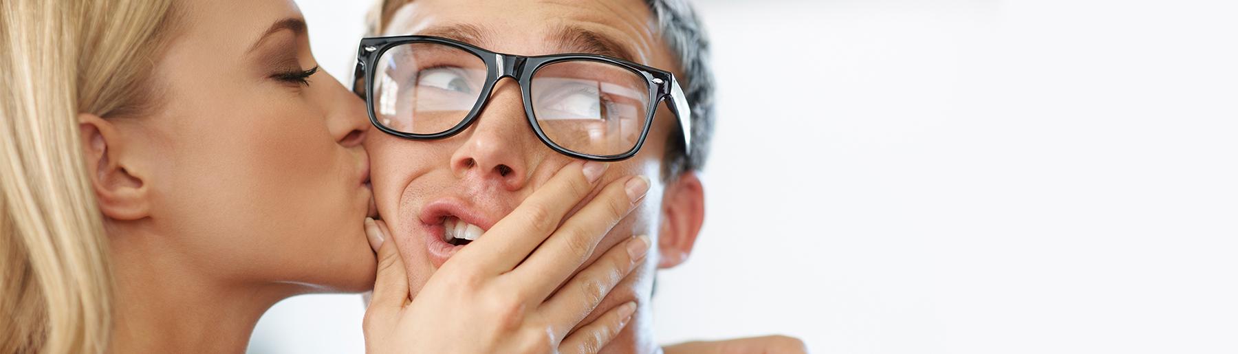 woman kissing man with glasses